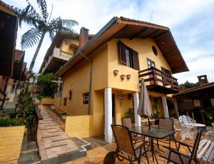 a table and chairs in front of a house at Pousada Bela Vista in Monte Verde