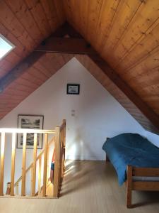 a room with a bed and stairs in a attic at Gite de Kergrist in Paimpol