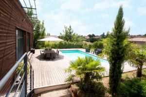 a swimming pool with a patio and an umbrella at Les Crays de Levigny in Charnay-lès-Mâcon