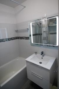 La salle de bains est pourvue d'un lavabo, d'une baignoire et d'un miroir. dans l'établissement 5 avenue de la Gavine Résidence Hyères Parc, à Hyères