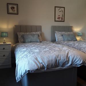 a bedroom with two beds and a night stand with two lamps at Kingsleigh Guest House in Lowestoft