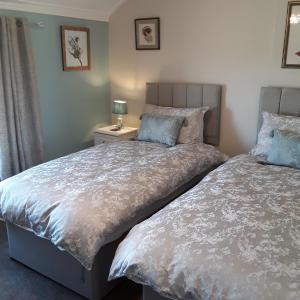 a bedroom with two beds and a lamp on a table at Kingsleigh Guest House in Lowestoft