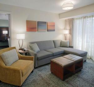 Staybridge Suites Fayetteville, an IHG Hotel في فايتيفيل: غرفة معيشة مع أريكة وكرسي