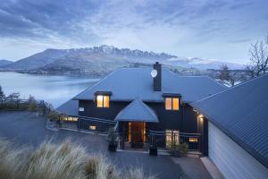 a black house with a view of a lake and mountains at Panorama House by Sotheby's Luxury Rental Homes in Queenstown