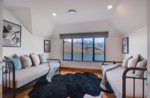 a living room with two beds and a large window at Panorama House by Sotheby's Luxury Rental Homes in Queenstown