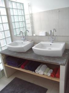 La salle de bains est pourvue de 2 lavabos et de serviettes. dans l'établissement Louise Chatelain suites, à Bruxelles