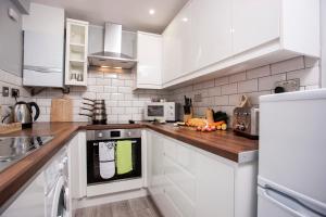 a kitchen with white cabinets and a wooden counter top at Dene View By Horizon Stays in Darlington