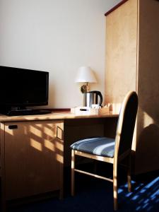 Habitación con escritorio con silla y TV. en Boutique Hotel Villa Stockum en Düsseldorf