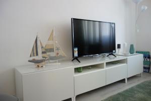 TV en un centro de entretenimiento blanco en una sala de estar en Peniche4you, en Peniche