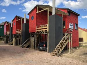 a row of colorful houses with a car parked outside at Norwood Eco Cabañas in Punta Del Diablo