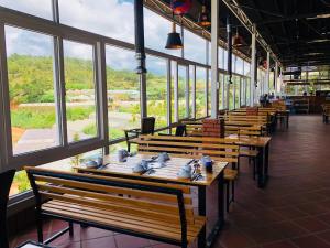 a row of wooden benches in a restaurant with windows at Berry Valley Homestay in Da Lat