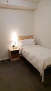 a bedroom with a bed and a night stand with a lamp at 2 bedrooms CBD FREE Tram apartment (Melb Central, China Town, Queen Victoria Market, Melbourne University, RMIT, etc) in Melbourne