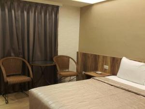 een hotelkamer met een bed en twee stoelen bij Non Lai Inn in Kaohsiung