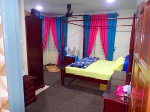 una camera con letto a baldacchino con tende rosse e blu di RizQin Homestay Bachok a Bachok