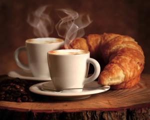 zwei Tassen Kaffee und ein Croissant auf dem Tisch in der Unterkunft Happy Village in La Giustiniana