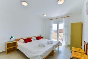 a white bedroom with a bed and a window at Apartments Citrus in Turanj