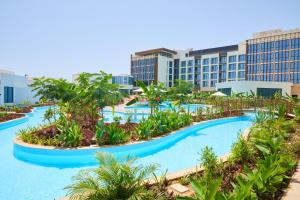 Millennium Resort Salalah في صلالة: منتجع فيه مسبح كبير فيه اشجار ومباني