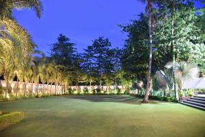 a large green yard with palm trees and a fence at KL7 Hotel & Banquets in Patna
