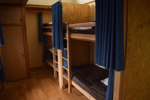 a room with two bunk beds with blue curtains at Guest House Minato in Miyako