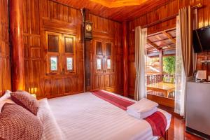 Athithara Homestay في فرا ناخون سي أيوتثايا: غرفة نوم بجدران خشبية وسرير في غرفة