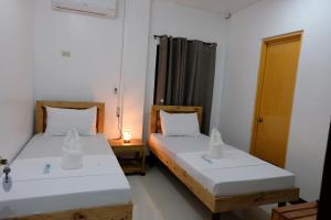dwa łóżka siedzące obok siebie w pokoju w obiekcie Bangles Homestay w mieście Coron