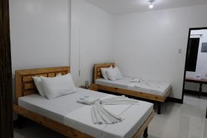 2 camas en una habitación con paredes blancas en Bangles Homestay, en Corón