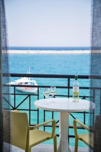a table with two glasses and a bottle on a balcony at Samaina Port Hotel in Karlovasi