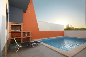 uma piscina com uma cadeira ao lado de uma casa em Paradise Terrace House em Quinta do Conde