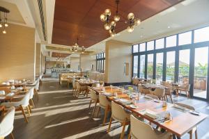 a restaurant with tables and chairs and large windows at Millennium Resort Salalah in Salalah