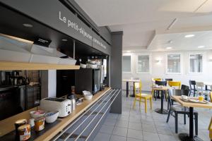 a restaurant with a counter with yellow chairs and tables at B&B HOTEL CHATEAUROUX Aéroport in Déols