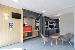 une salle d'attente avec des chaises, une table et une télévision dans l'établissement B&B HOTEL CHATEAUROUX Aéroport, à Déols