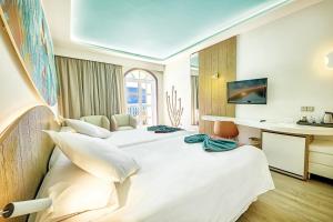 a hotel room with two beds and a desk at Hotel LIVVO Puerto de Mogán in Puerto de Mogán