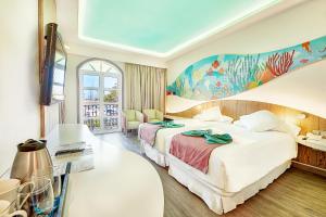 プエルト・デ・モガンにあるHotel LIVVO Puerto de Mogánのベッド2台が備わる客室で、壁には絵画が飾られています。