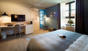 Schlafzimmer mit einem Bett, einem Schreibtisch und einem TV in der Unterkunft Marias Platzl in München