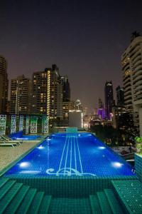 a large swimming pool with a city skyline at night at Hope Land Hotel Sukhumvit 8 in Bangkok