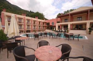 an outdoor patio with tables and chairs in front of a building at 4 Epoxes Hotel Spa in Kato Loutraki