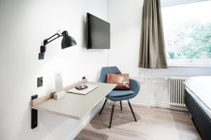 Habitación con escritorio, silla y cama. en Hotel Town Living, en Ringkøbing