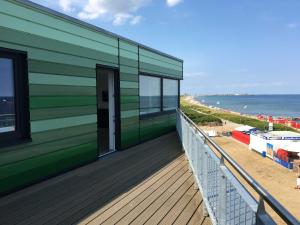 a green building on the beach next to the ocean at Strandappartements Haus Strandkieker in Schönhagen