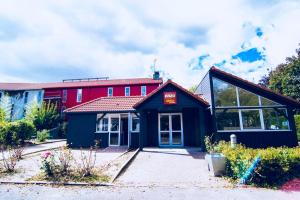 a red and black building with a red sign on it at Enzo Hotels Trappes by Kyriad Direct in Trappes