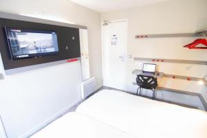 ein Schlafzimmer mit einem Bett und einem TV an der Wand in der Unterkunft Enzo Hotels Trappes by Kyriad Direct in Trappes