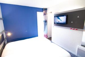 a bedroom with a bed and a tv on a wall at Kyriad direct Trappes in Trappes