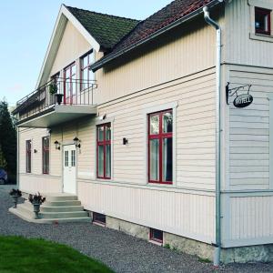 een wit huis met rode ramen en een balkon bij Villa Göta in Forsvik