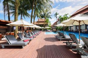 a row of lounge chairs and umbrellas next to a swimming pool at Khaolak Oriental Resort - Adult Only in Khao Lak