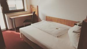 a bedroom with a bed with a desk and a window at Hotel Jägerhof in Roth +15 photos