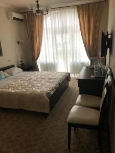 a bedroom with a bed and a chair and a window at Vesta Guest House in Kislovodsk