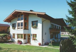 ein weißes Haus mit Fenstern und einem Zaun in der Unterkunft Apartment Landhaus Krall in Westendorf