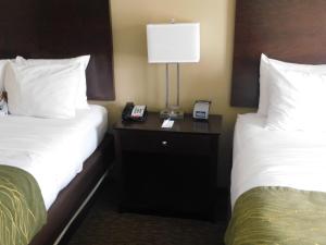 a hotel room with two beds and a lamp on a night stand at Comfort Inn in Saint Clairsville
