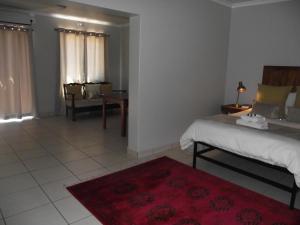 a bedroom with a bed and a red rug at De Nachtuilen Guesthouse in Upington