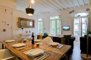 Un comedor con una mesa con platos y copas de vino. en Verdura Suites ArchSense Apartments, en Pontevedra