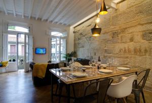Un comedor con una mesa y una pared de piedra. en Verdura Suites ArchSense Apartments, en Pontevedra